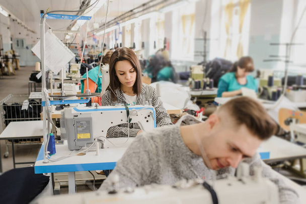 крупним планом фото молодого чоловіка та інших швачок для шиття швейною машинкою на фабриці
 - Фото, зображення