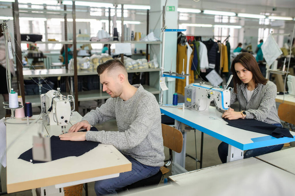 cerca de la foto de un joven y otras costureras cosiendo con la máquina de coser en una fábrica - Foto, imagen