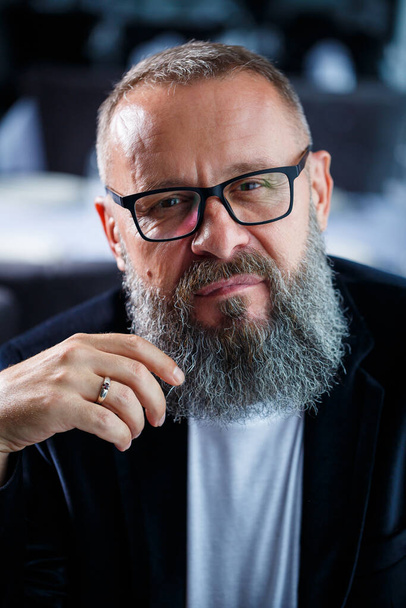 Retrato de un adulto de pelo gris hombre de éxito con un hombre de negocios barba con gafas con una cara seria en una chaqueta - Foto, Imagen