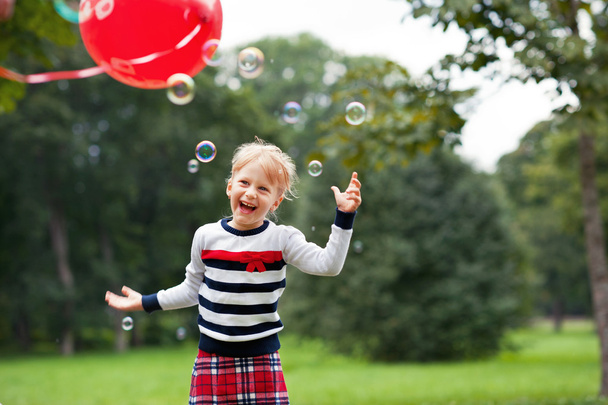 笑玩肥皂泡泡在公园里的金发小姑娘公園でシャボン玉遊び金髪少女の笑い - 写真・画像