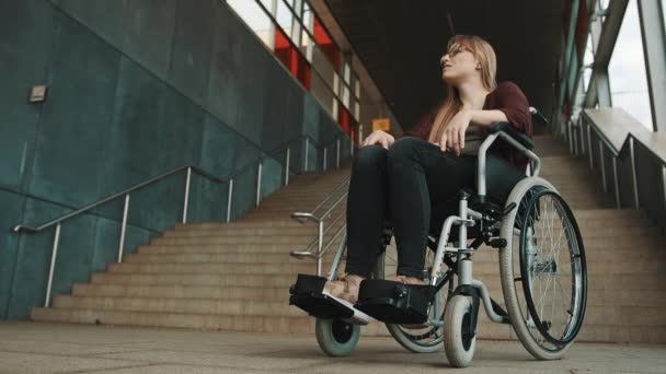 Merdiven önünde tekerlekli sandalyede oturan, cesareti kırılmış, beyaz bir kadın. - Video, Çekim
