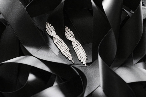 Luxury diamond earrings on black silk ribbon as background, jewelry and fashion brand - Photo, Image