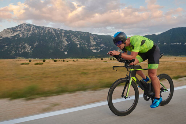 triathlon athlete riding professional racing bike at workout on curvy country road - Photo, Image