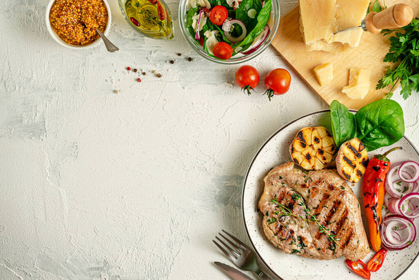 Homemade grilled pork steak with vegetables, spices and parmesan cheese on concrete background. Overhead, copy space. - Photo, Image