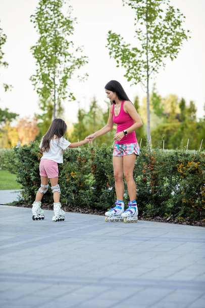 Young mother and her little daughter rollerskating - Photo, image
