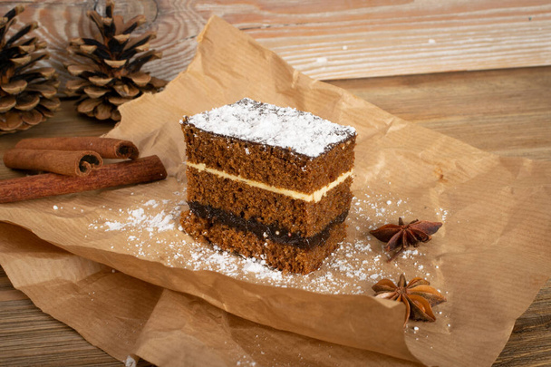 Παραδοσιακό βερνίκι χριστουγεννιάτικη έρημο piernik, pryanik ή παντεσπάνι κέικ με μπαχαρικά. Ορθογώνιο κομμάτι τάρτας κακάο, μελόψωμου ή μπισκότων με στρώσεις - Φωτογραφία, εικόνα