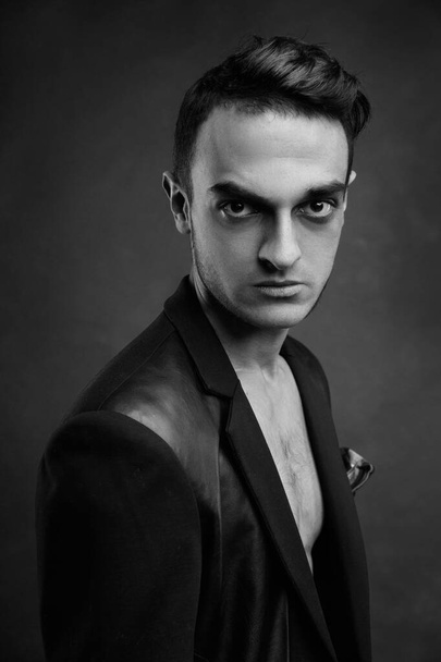 Black and white portrait of a gloomy young man in a jacket over his naked body. - Foto, immagini