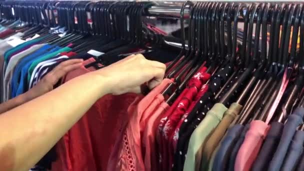 Close-up of female hands plucked a hanger with clothes. Woman's hands run across a rack of clothes. Dolly shot from the side. Woman's hand smoothing a colorful clothes. Close-up a hanger for clothing - Footage, Video