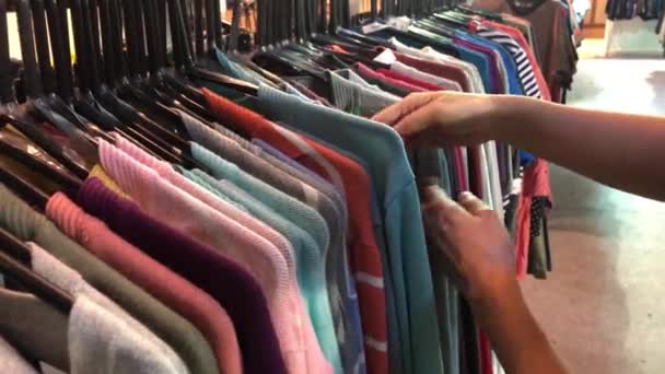 Close-up of female hands plucked a hanger with clothes. Woman's hands run across a rack of clothes. Dolly shot from the side. Woman's hand smoothing a colorful clothes. Close-up a hanger for clothing - Footage, Video