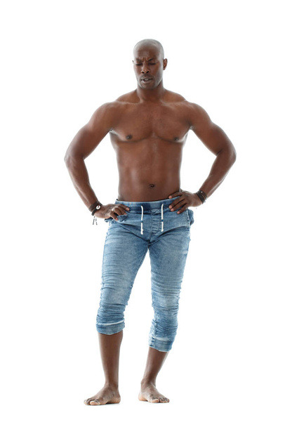 Athletic young black man in jeans and with a nude torso is standing in full growth isolated on white background. - Photo, Image