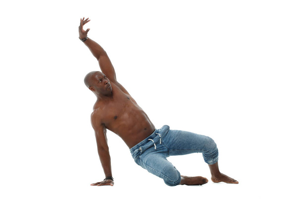 Atletico giovane nero in jeans e con un busto nudo che balla isolato su sfondo bianco. - Foto, immagini