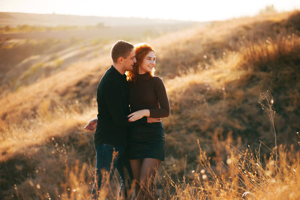 Una foto de una pareja abrazada ambos mirando en una dirección en un campo - Foto, Imagen