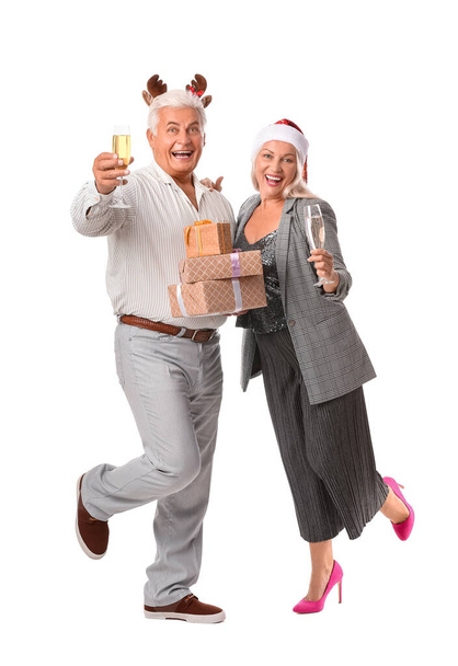 白い背景にクリスマスの贈り物とシャンパンと高齢者のカップル - 写真・画像