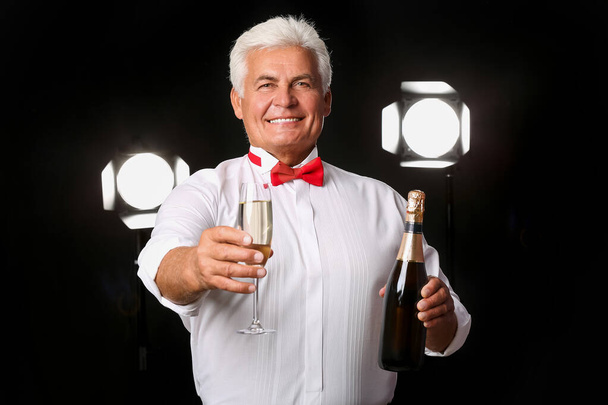 Elderly man with champagne on dark background - Photo, Image