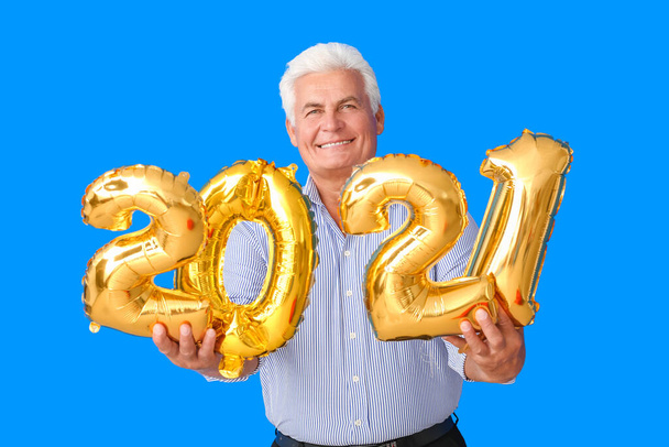 Elderly man with figure 2021 on color background. New Year celebration - Photo, Image