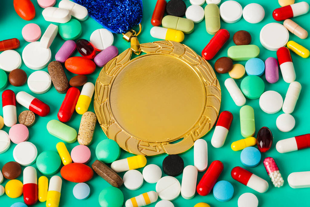 Gold medal and pills on green background - Photo, image