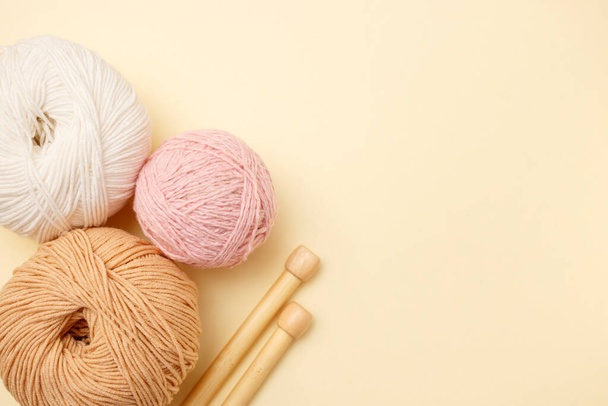 White and brown knitting wool and knitting needles on pastel background. Top view, flat lay, copy space. - Φωτογραφία, εικόνα