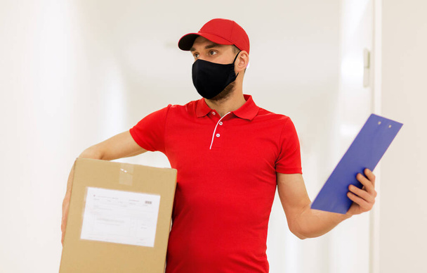 delivery man in mask with box and clipboard - Foto, immagini