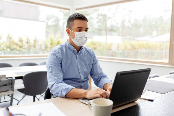 man in mask with laptop working at home office - Foto, Imagem