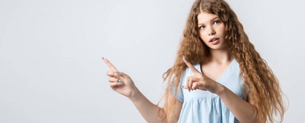 You better see it. Intrigued European girl with curly long hair, points away with both for fingers, shows blank space for your promotion. People, advertisement concept - Fotoğraf, Görsel