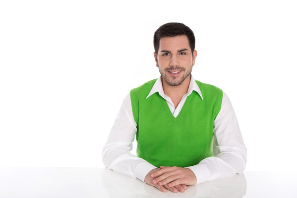 Isolated young smiling businessman sitting at desk on white.  - Foto, Bild