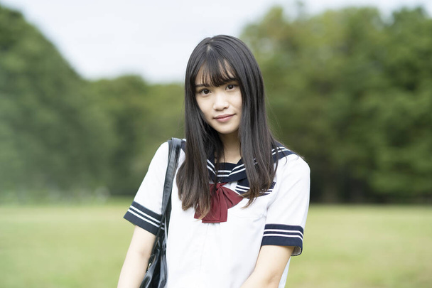 asiatico femmina scuola superiore studente sorridente in uniforme all'aperto - Foto, immagini