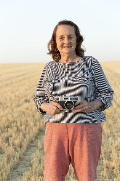 Retrato de uma mulher idosa com uma câmera analógica no campo. - Foto, Imagem
