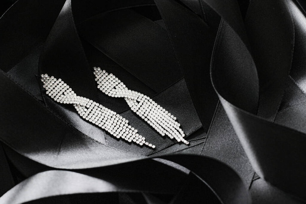 Orecchini di diamanti di lusso su nastro di seta nera come sfondo, gioielli e marca di moda - Foto, immagini