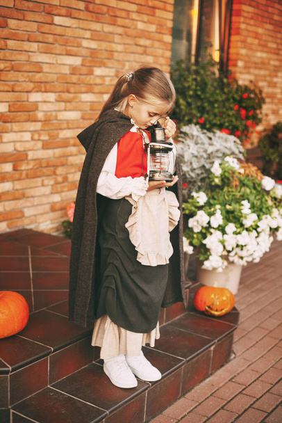 Маленькая девочка в сказочном костюме с корзиной в руках во время празднования Хэллоуина идет посетить для удовольствия - Фото, изображение