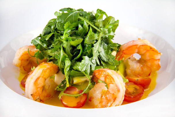 Salad with king prawns, arugula, tomatoes, avocado. Closeup on a white plate. - Foto, Bild