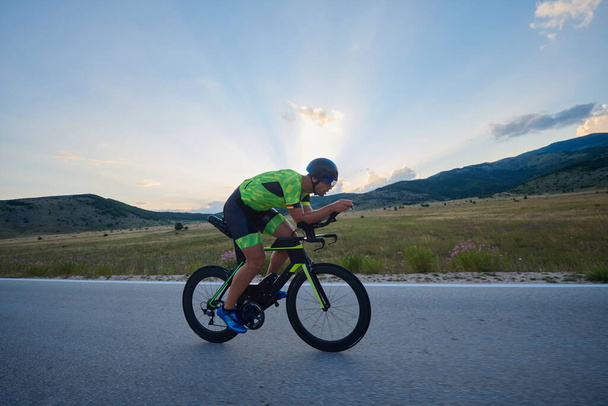 triathlon athlete riding professional racing bike at workout on curvy country road - Foto, Imagen