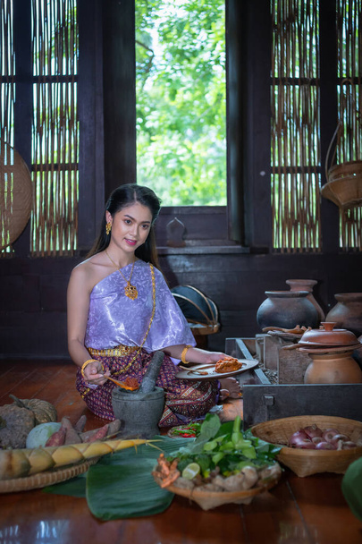 Beautiful portrait Asian woman wearing Thai dress costume traditional according culture and tradition cooking in the kitchen at the ancient house Ayutthaya, Thailand - Photo, image