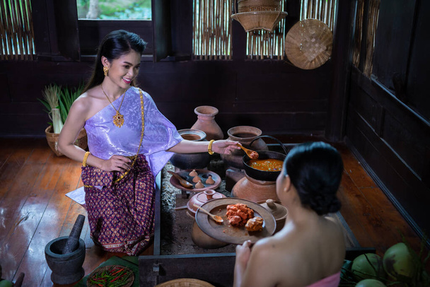 Beautiful portrait Asian woman wearing Thai dress costume traditional according culture and tradition cooking in the kitchen at the ancient house of Ayutthaya province, Thailand - Photo, image