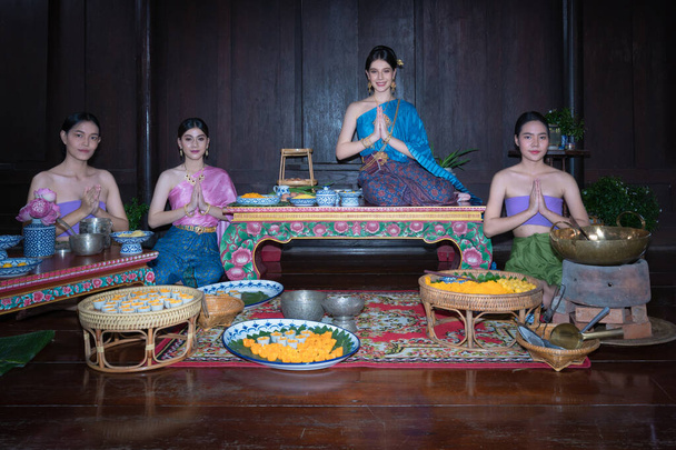 Beautiful portrait group of Asian woman wearing Thai dress costume traditional according culture sit and pay respect with hands to worship in Thai style at ancient house Ayutthaya, Thailand - Photo, image