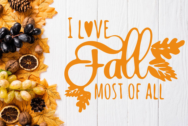 top view of autumnal decoration and grapes near i love fall most of all lettering on white wooden background - Photo, Image
