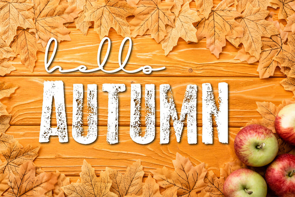 bovenaanzicht van rijpe appels en bladeren bij hallo herfst belettering op houten achtergrond - Foto, afbeelding