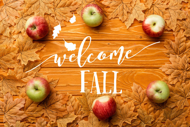 Ansicht von reifen Äpfeln und Blättern in der Nähe von Willkommensbuchstaben im Herbst auf Holzgrund - Foto, Bild