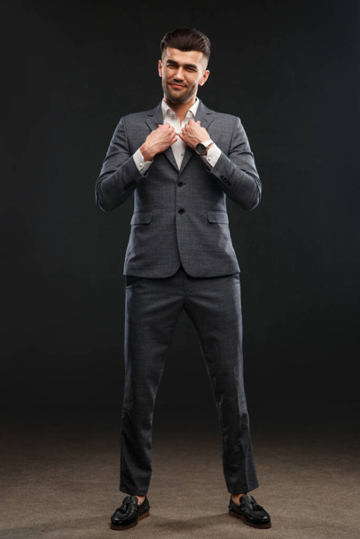 An elegant man in a business suit stands in full growth against a dark background. - Foto, Imagem