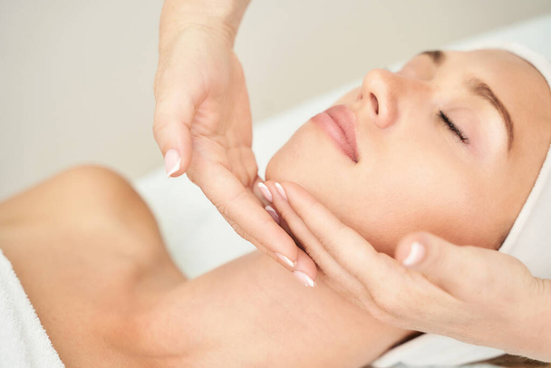 Beautiful portrait on white background. Cosmetology massage. Young woman - Фото, изображение