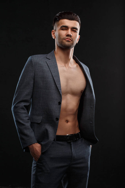Young sexy man in a jacket over his naked body against a dark background. - Foto, Bild