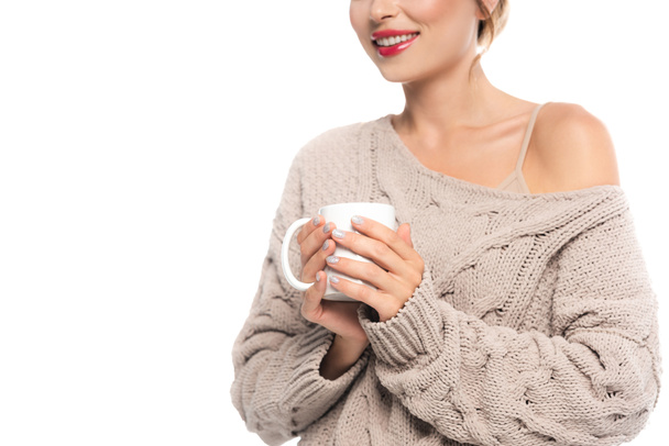 przycięty widok zadowolonej kobiety w ażurowym swetrze trzymając filiżankę ciepłego napoju odizolowany na białym - Zdjęcie, obraz