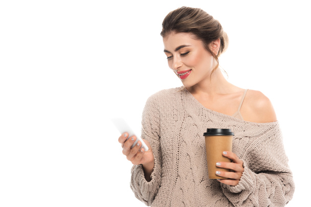 stylish woman in knitted sweater holding coffee to go while chatting on mobile phone isolated on white - Φωτογραφία, εικόνα