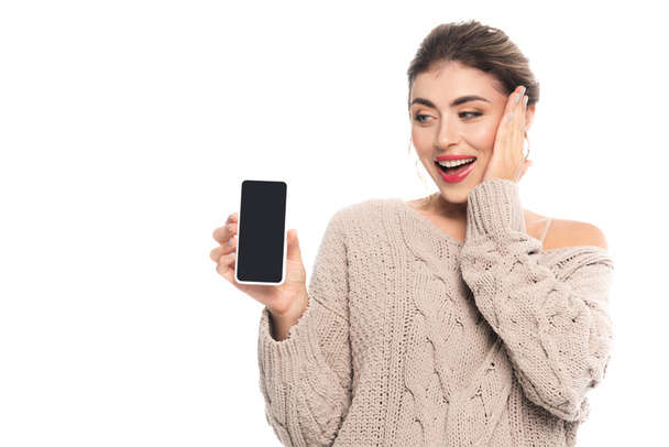 amazed woman holding smartphone with blank screen while touching face isolated on white - Фото, зображення