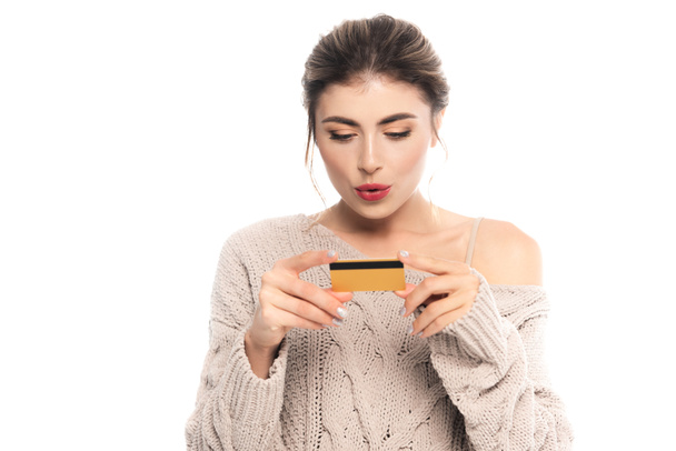 amazed woman in trendy knitted sweater holding credit card isolated on white - Foto, Imagem