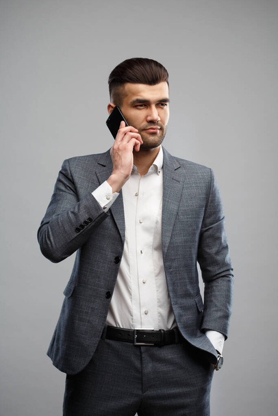 Young Asian man in a business suit talking on the phone Isolated on a gray background. - Fotoğraf, Görsel