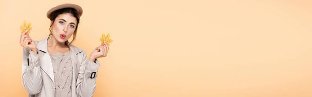 ιστοσελίδα κεφαλίδα του ενθουσιασμένοι γυναίκα στο μοντέρνο φθινοπωρινό ντύσιμο εκμετάλλευση κίτρινα φύλλα απομονώνονται σε ροδάκινο - Φωτογραφία, εικόνα