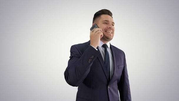 Businessman talking on mobile phone happily on gradient backgrou - Photo, image