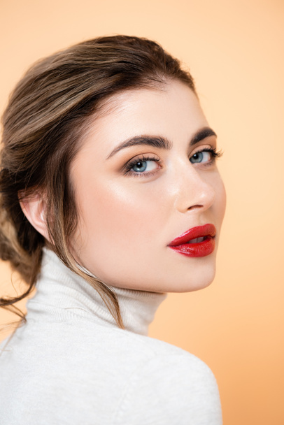 portrait of sensual woman with red lips looking at camera isolated on peach  - Photo, Image