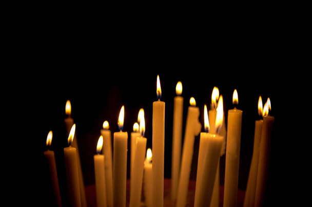Close-up van het branden en verlichten van kaarsen geïsoleerd over zwarte achtergrond, kerst decoratie, kerst achtergrond - Foto, afbeelding