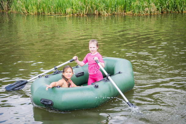 暑い夏の日、二人の少女がボートで泳いでいる。. - 写真・画像